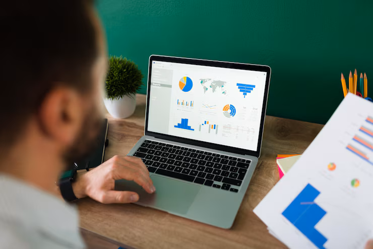 rear view young man working his laptop looking work report graphs